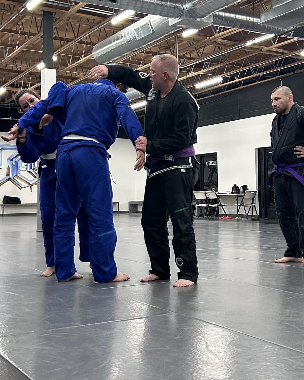 Mike Pelton coaching two officers through a technique on the mat